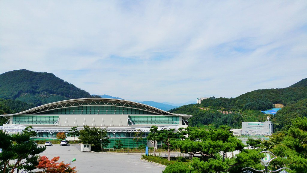 AI 廣告成本：綠意山丘前的現代大型場館建築