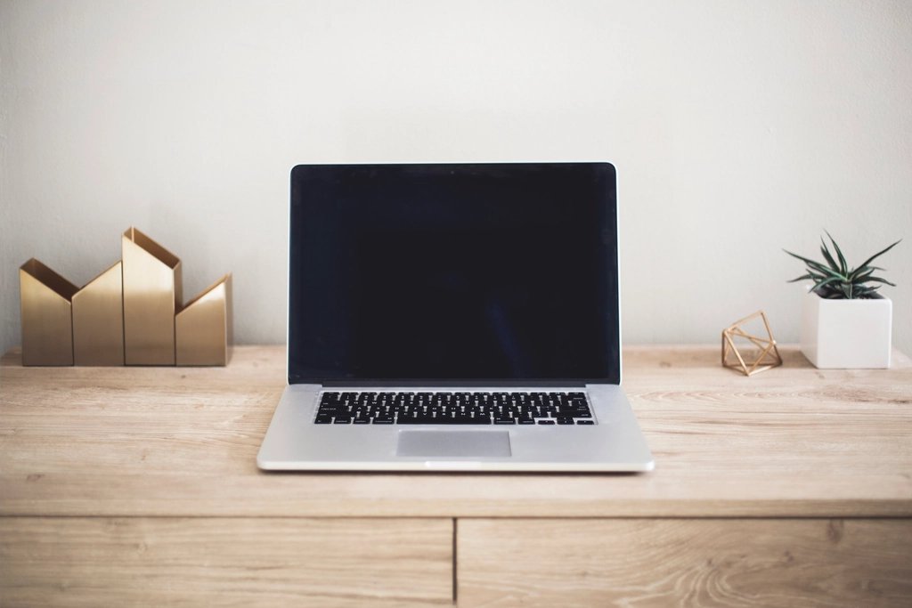數位行銷：木質辦公桌上的筆電，旁有盆栽與金色收納架